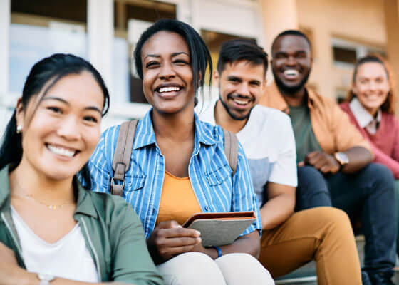 Multi Ethnic Group Of Happy College Students Enjoy Outdoors And Look At Camera.